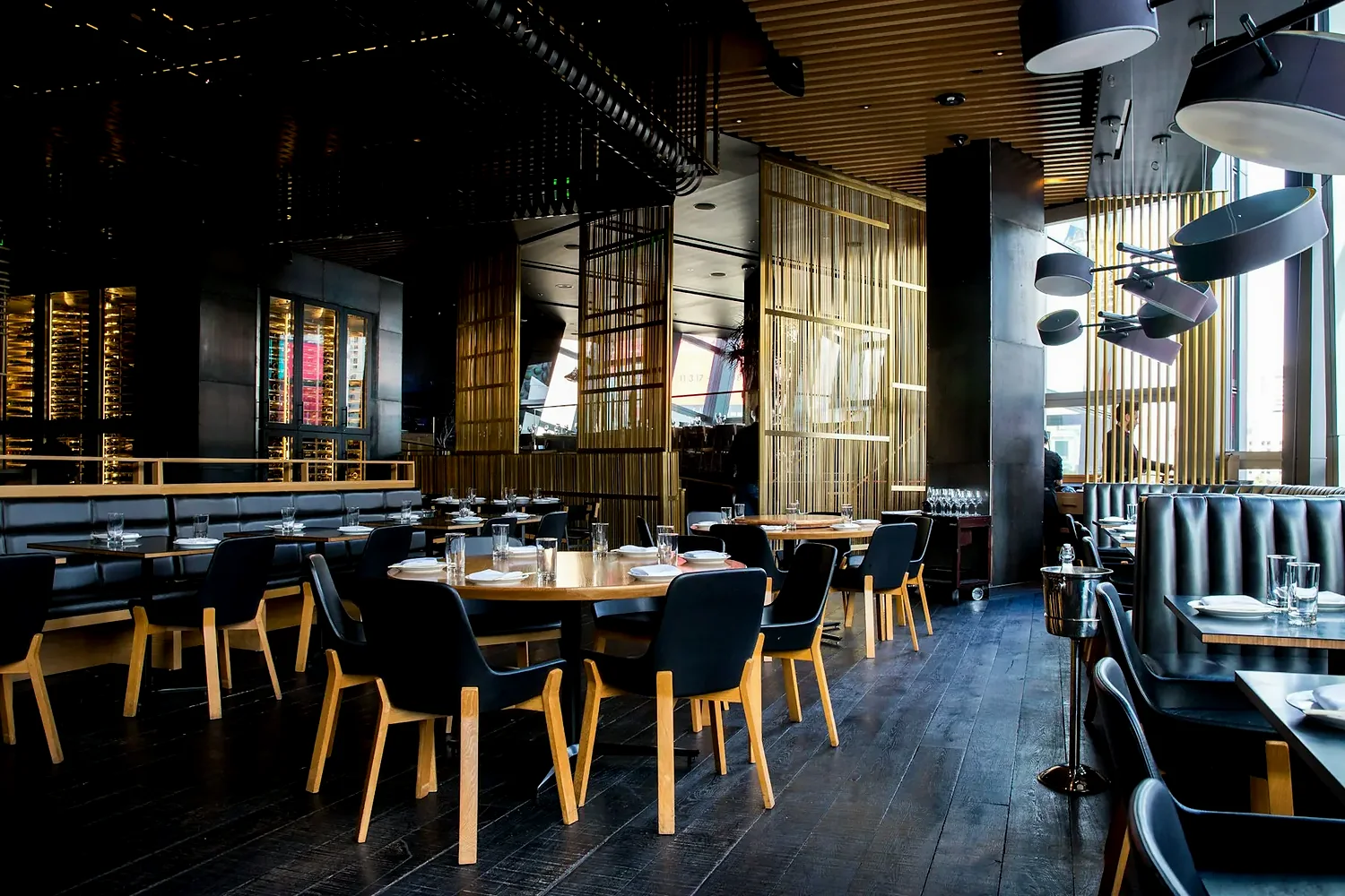 Set tables in a low-lit restaurant with brass screens and banquette seating