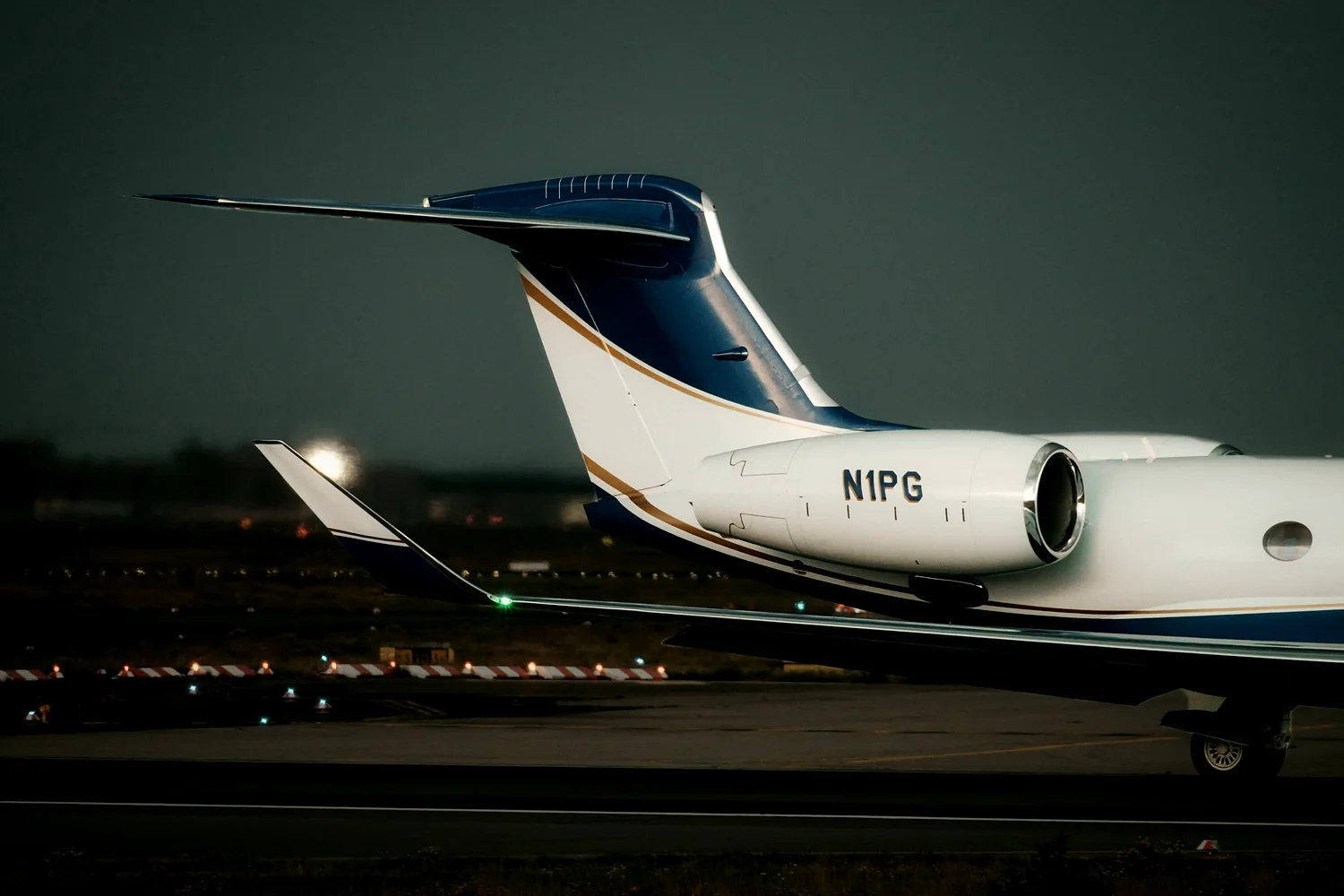 Private jet on the runway at dusk with taxiway lights beyond