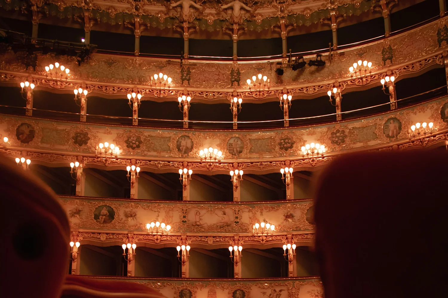 Tiers of gilded theatre boxes lit by candle-style sconces